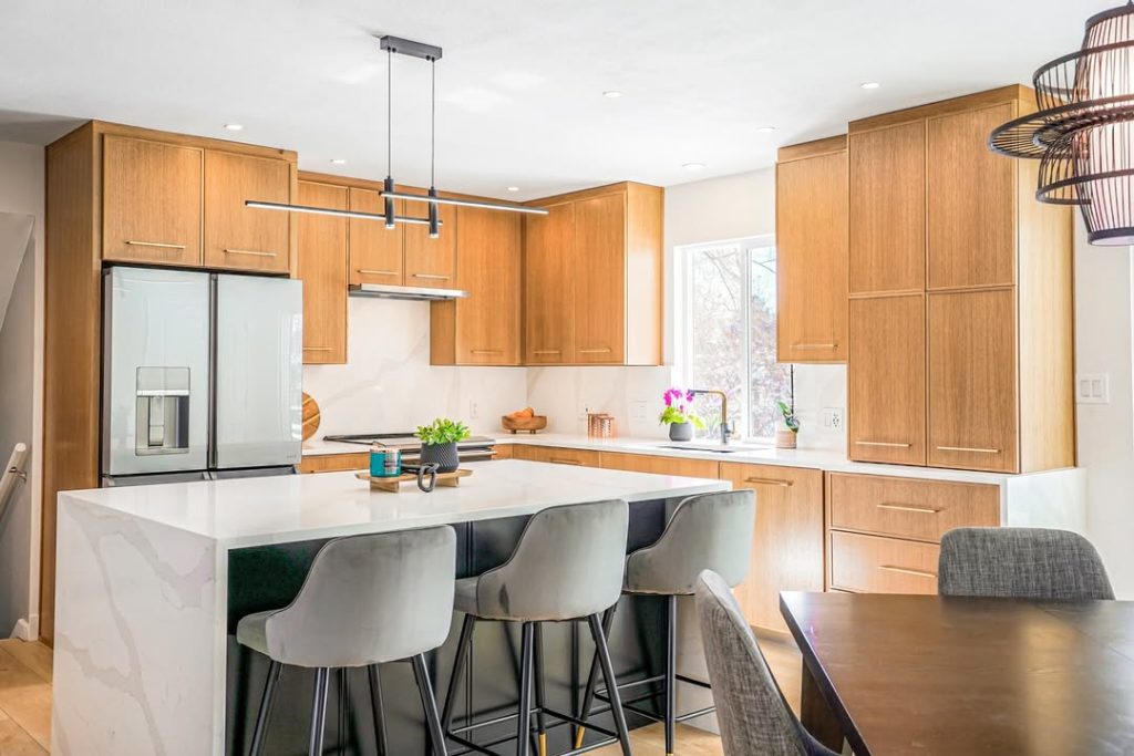 Light wood kitchen with white countertops and modern lighting