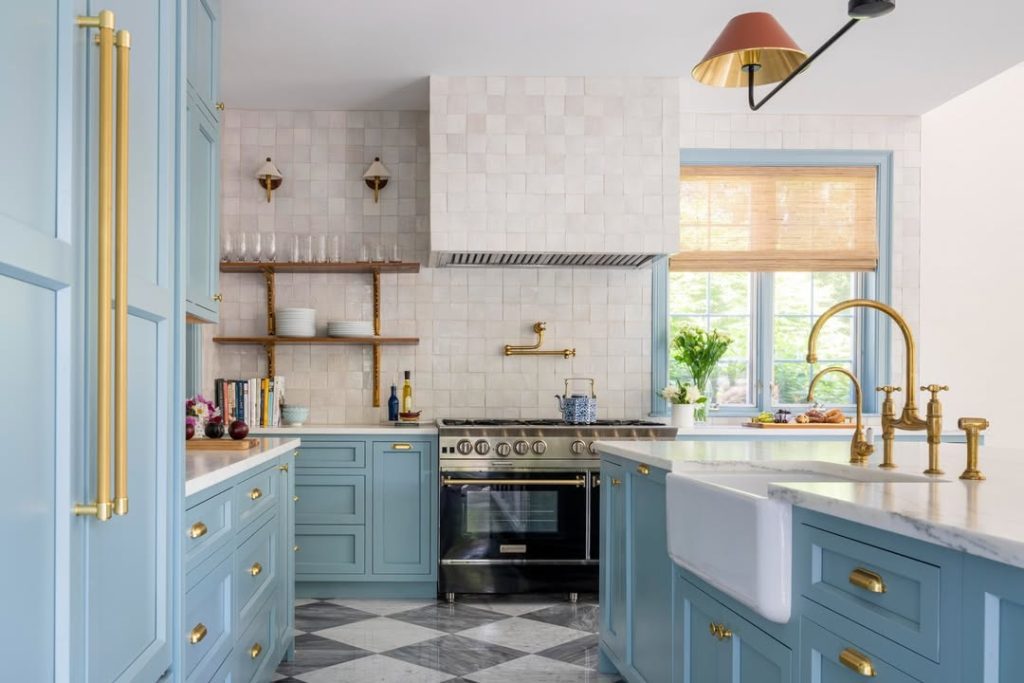 Light blue kitchen cabinets with white counters and brass