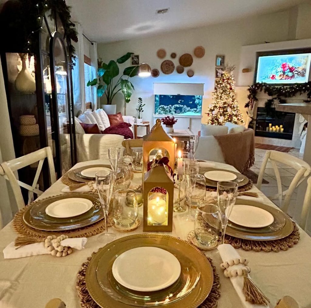Elegant Christmas table with golden plates, white chandelier, and natural greenery centerpiece