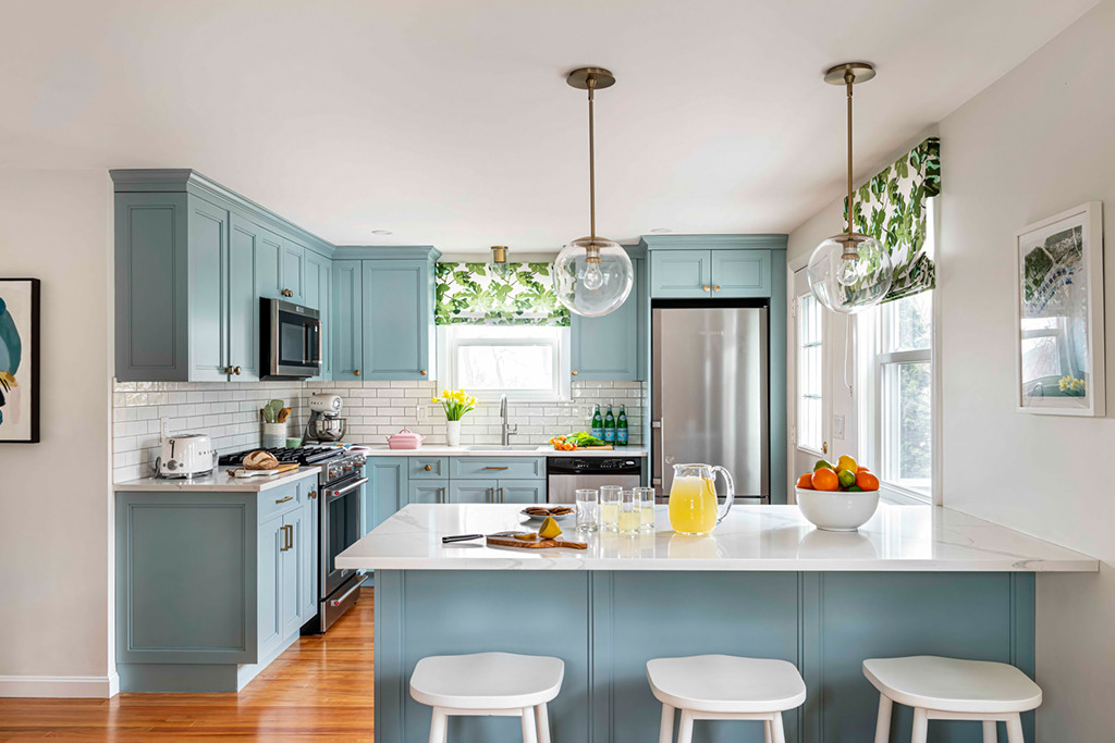 Blue kitchen with white island and pendant lighting