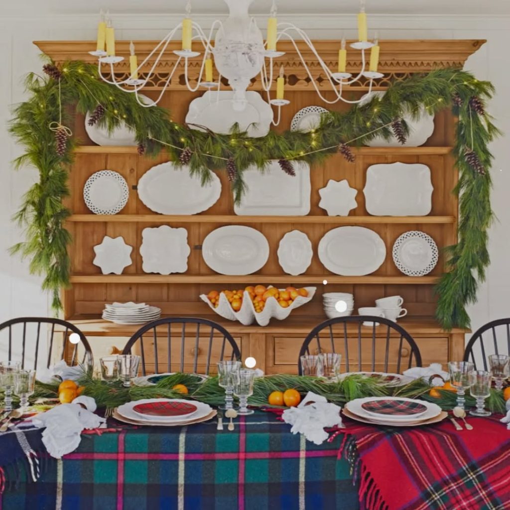 Christmas kitchen with evergreen garland on wooden shelves and plaid table runner