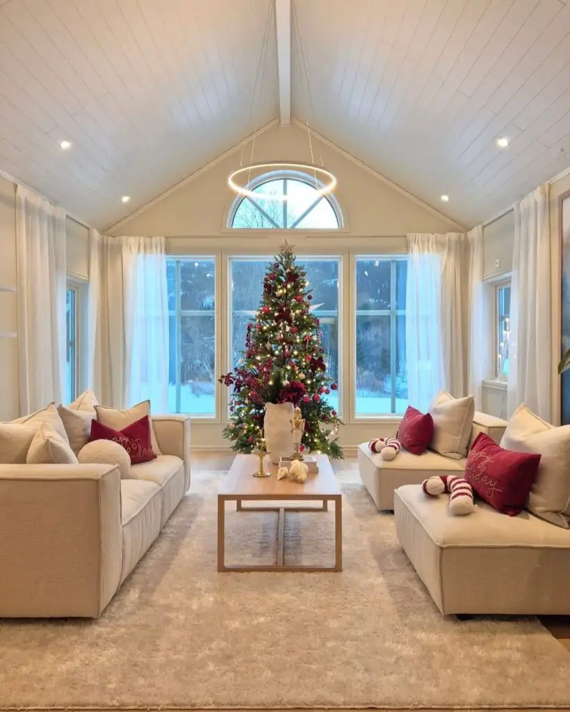 Bright living room with vaulted ceiling, arched window, Christmas tree, and symmetrical seating.