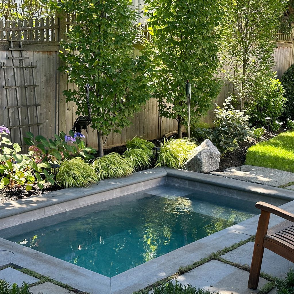 Small pool surrounded by lush garden landscaping and stone features