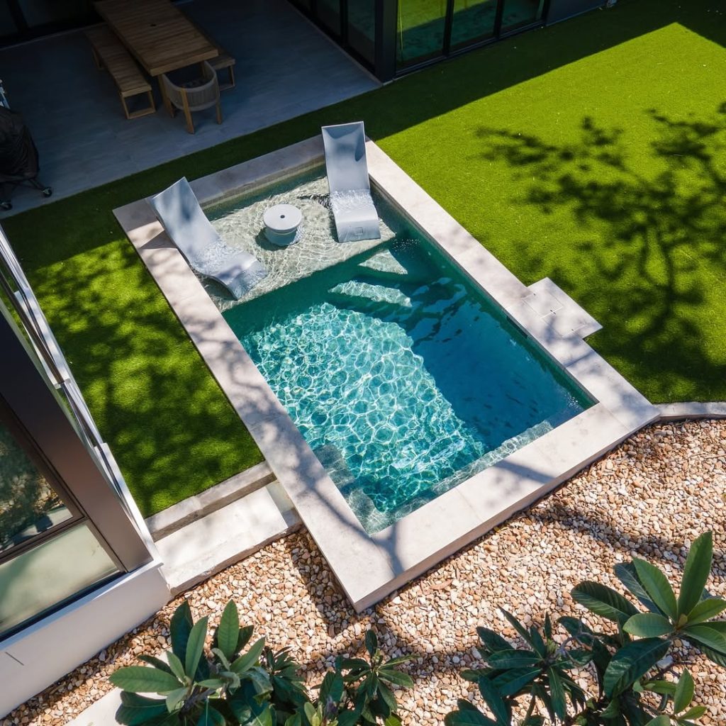 Aerial view of small pool with water spouts and green lawn