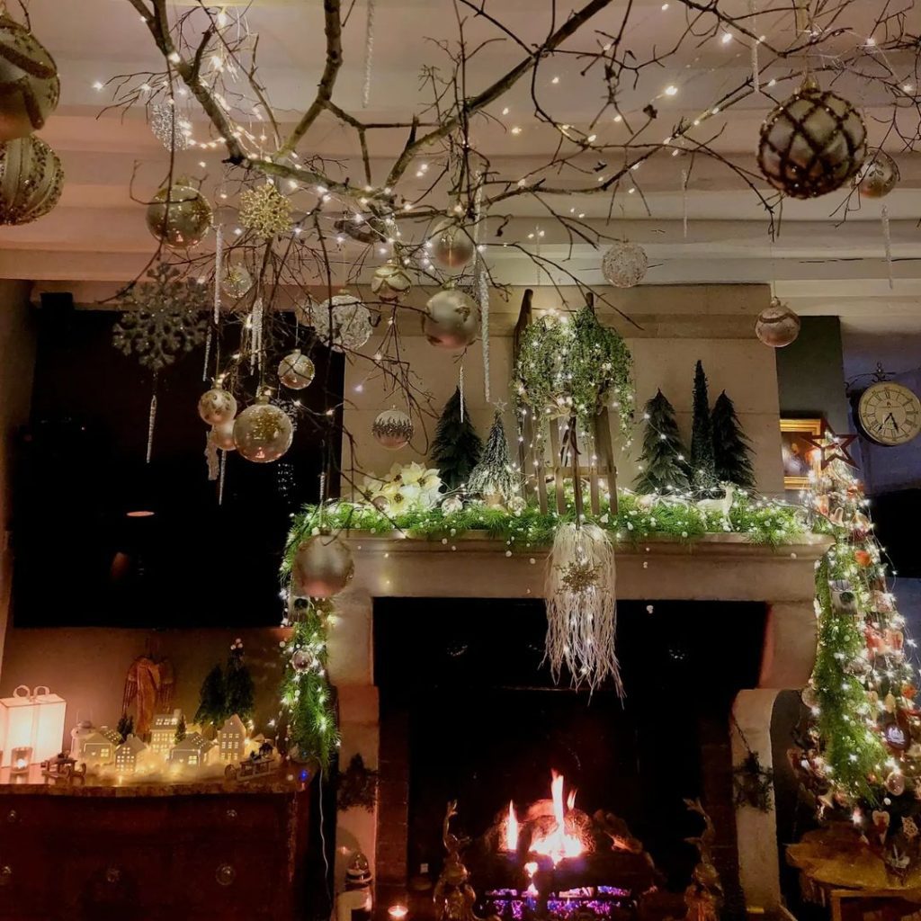 Christmas room with hanging branch ceiling decorations fireplace village and warm lighting