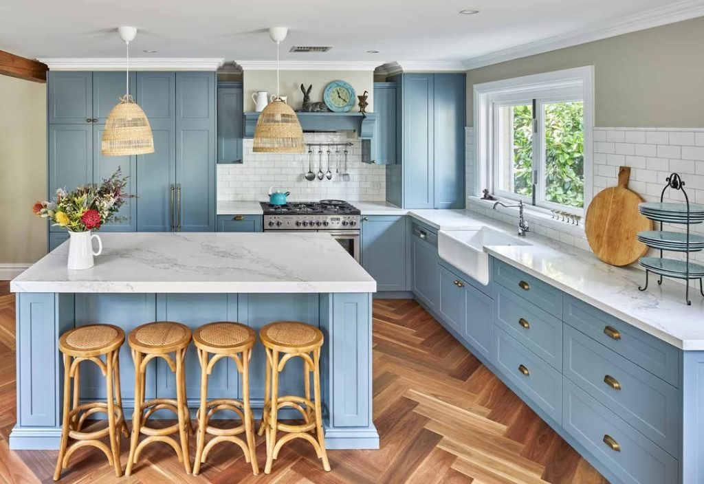 Blue coastal kitchen with wicker pendants and herringbone floors