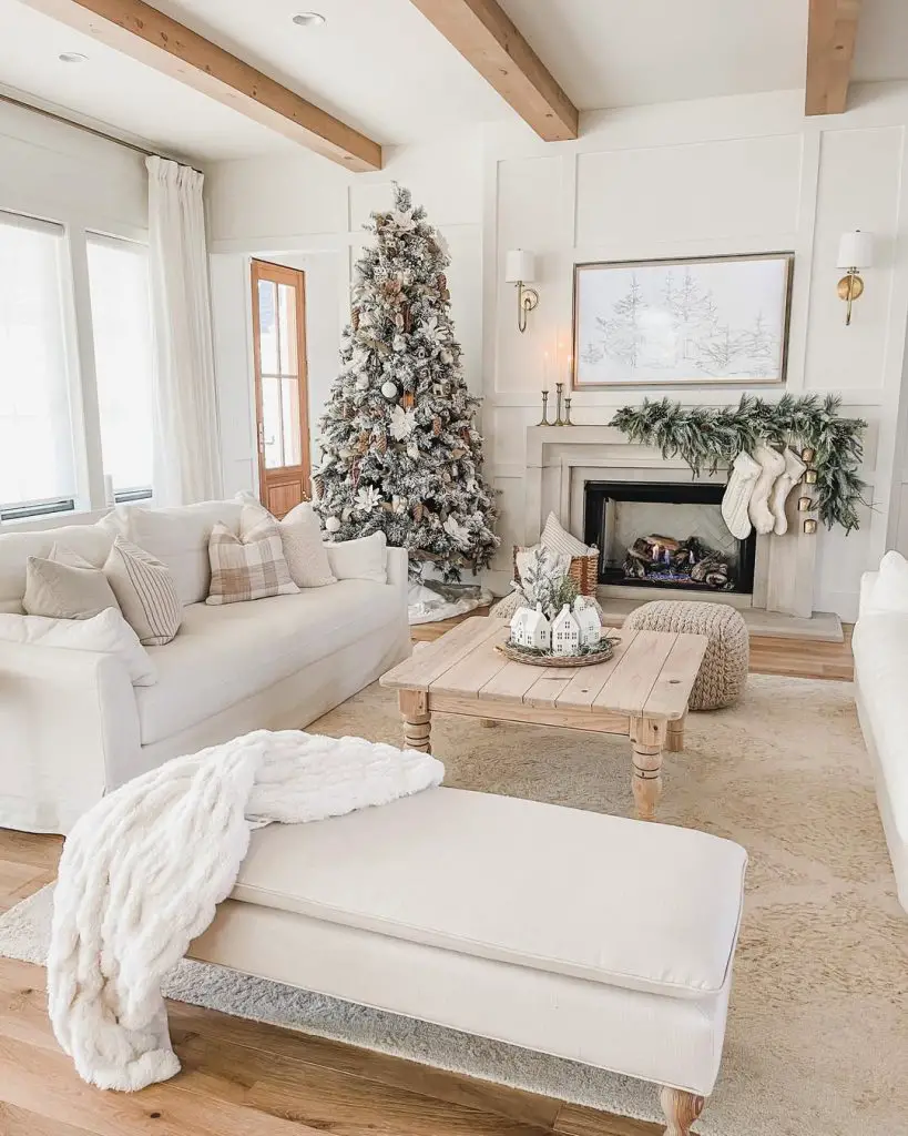 Farmhouse living room with white paneling, flocked Christmas tree, and neutral holiday decor.