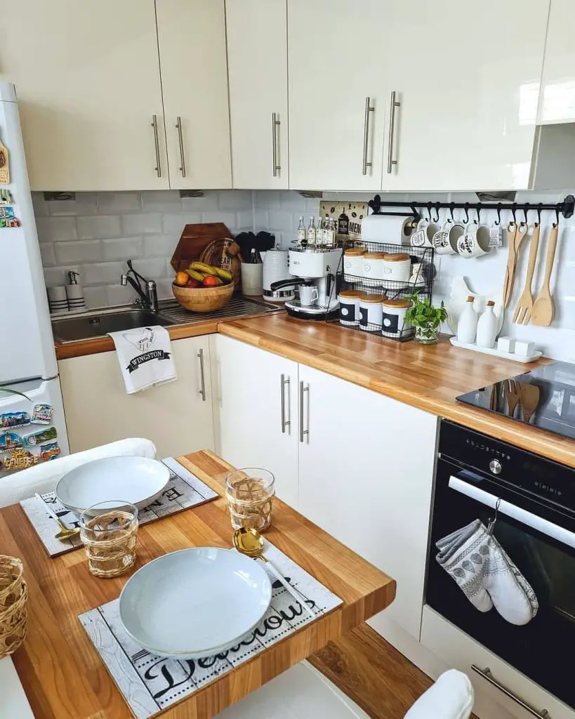 Small galley kitchen with white cabinets, wood counters, organized storage