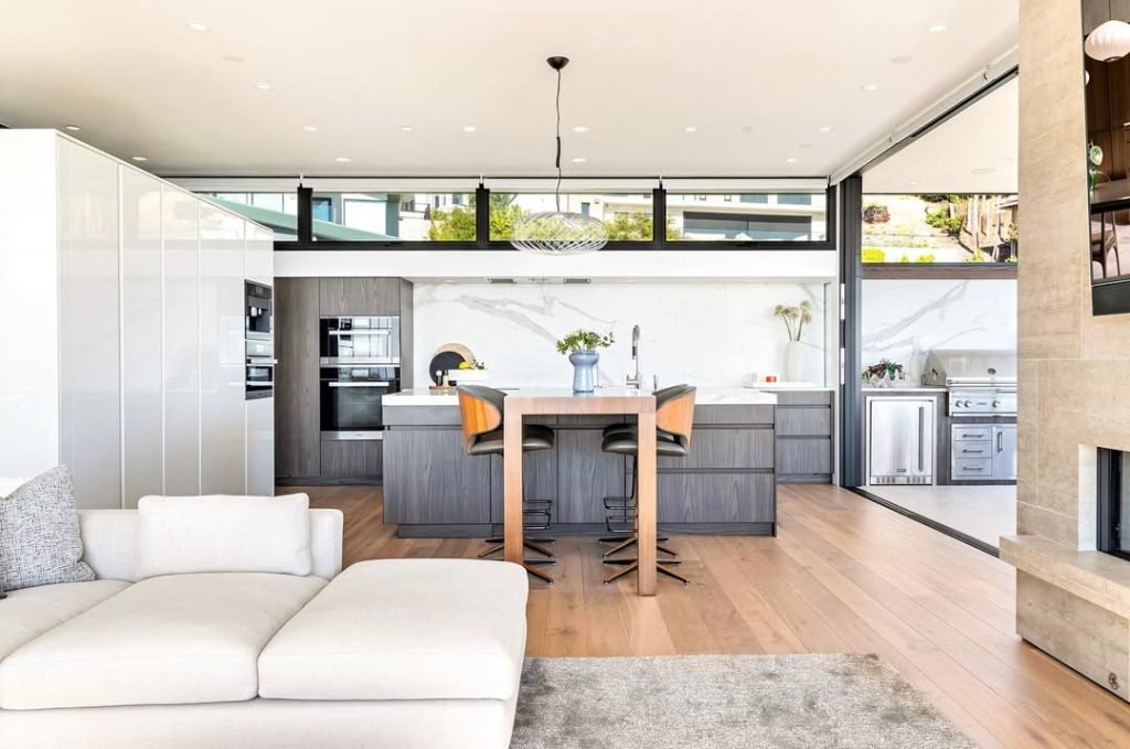 Open kitchen with floor to ceiling windows and gray cabinets
