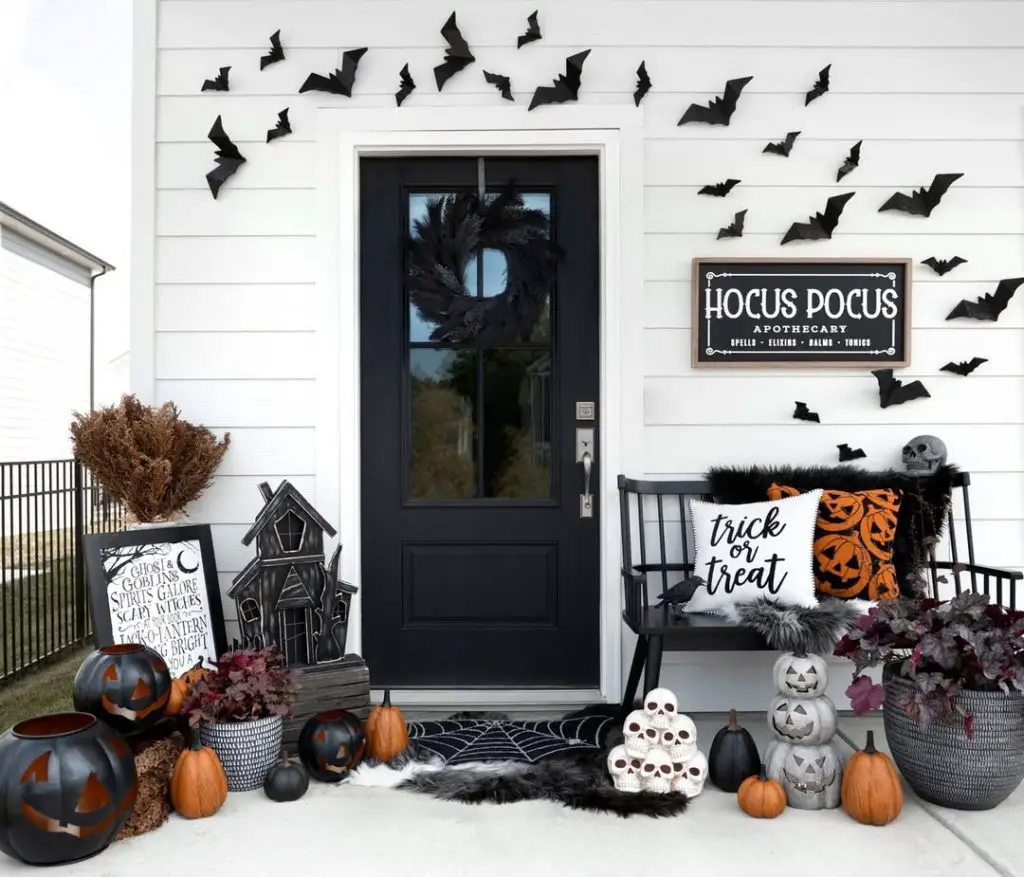 Halloween decorated front porch with black door paper bats pumpkins