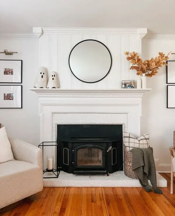 White fireplace mantel decorated with autumn pumpkins and dried flowers
