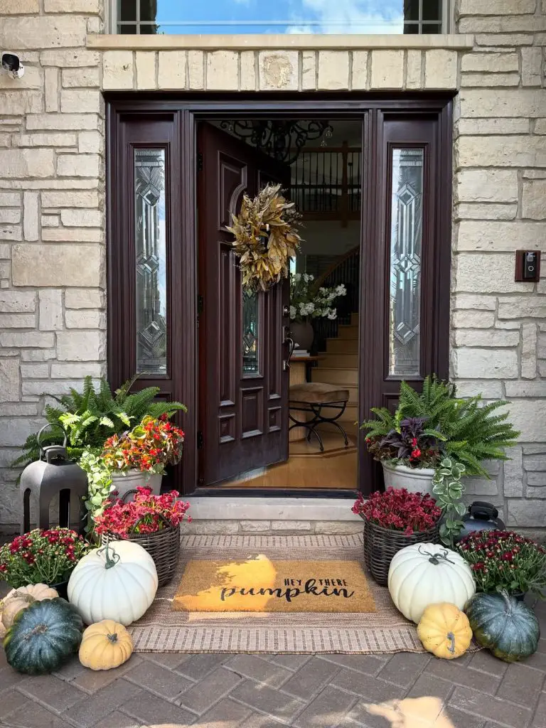 Stone entrance with burgundy mums and white pumpkins