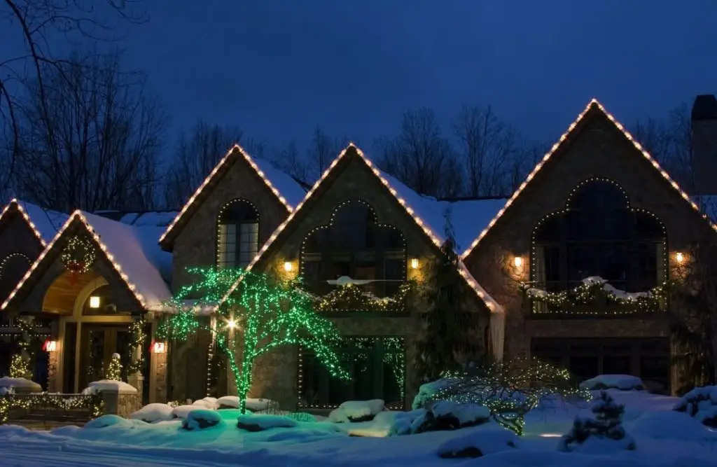 Front door decorated with illuminated joy letters and Christmas branches