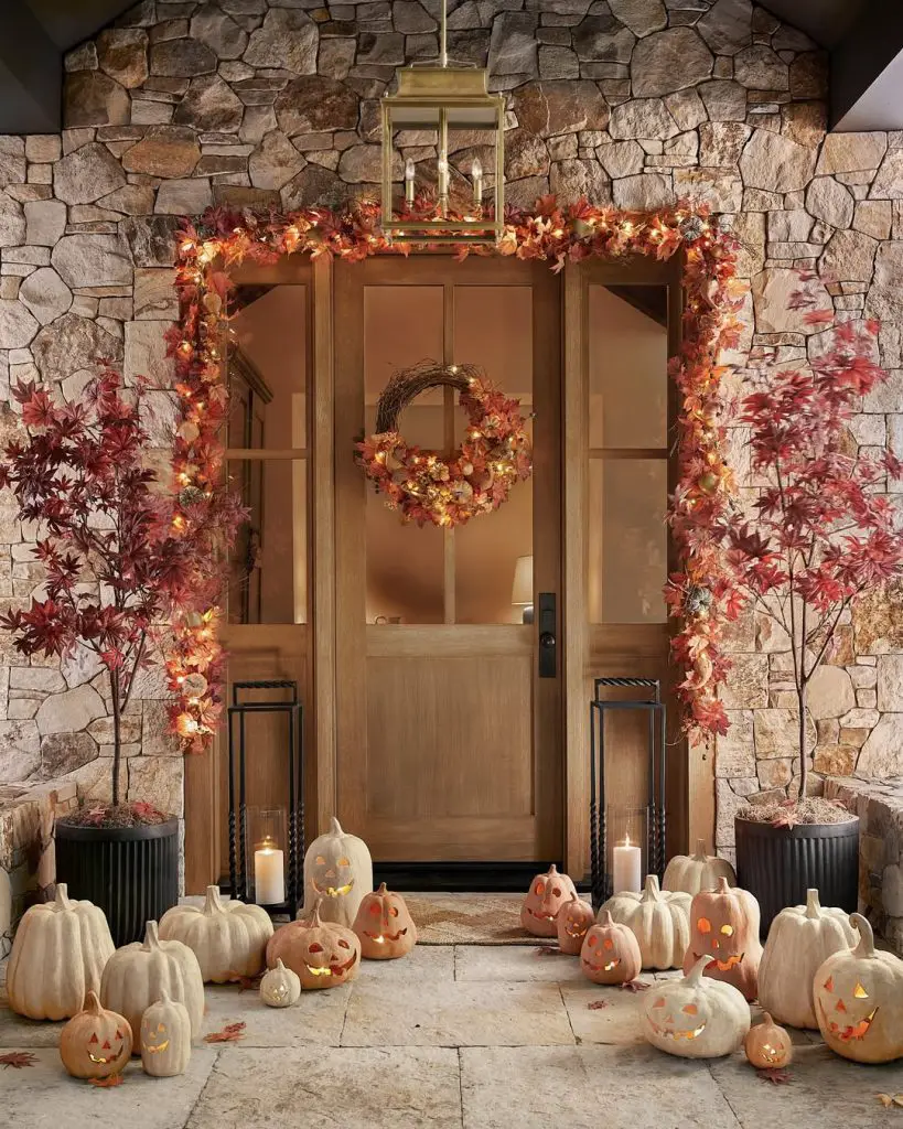 Stone entrance with lit autumn garland many carved pumpkins elegant