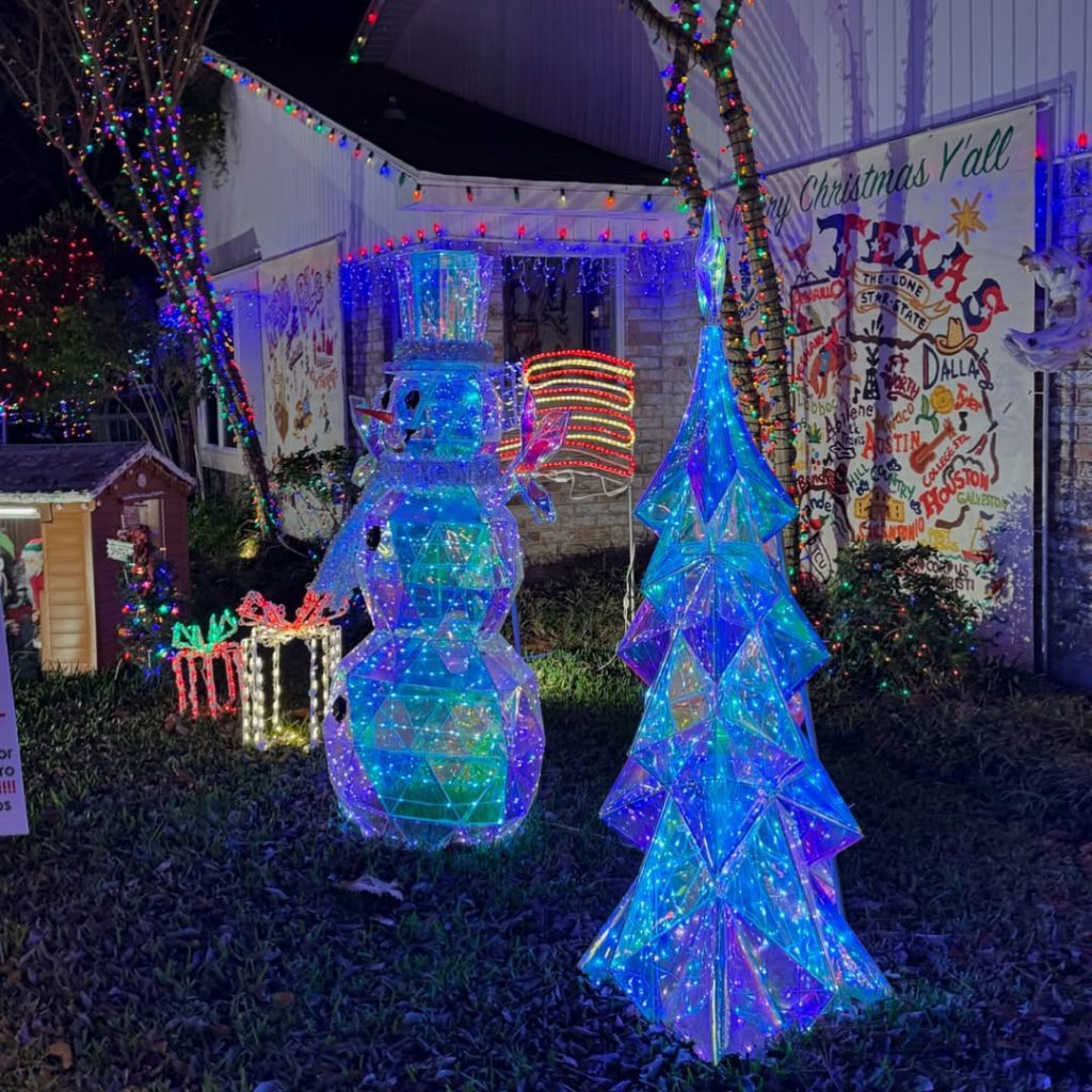 Blue wire frame Christmas trees with snowman in yard