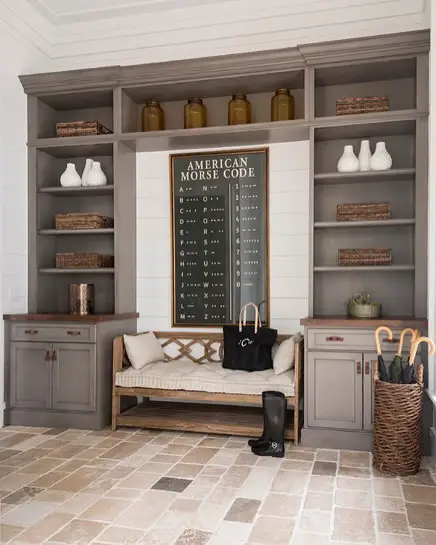 Gray mudroom with morse code chart, built-in shelving, and stone flooring