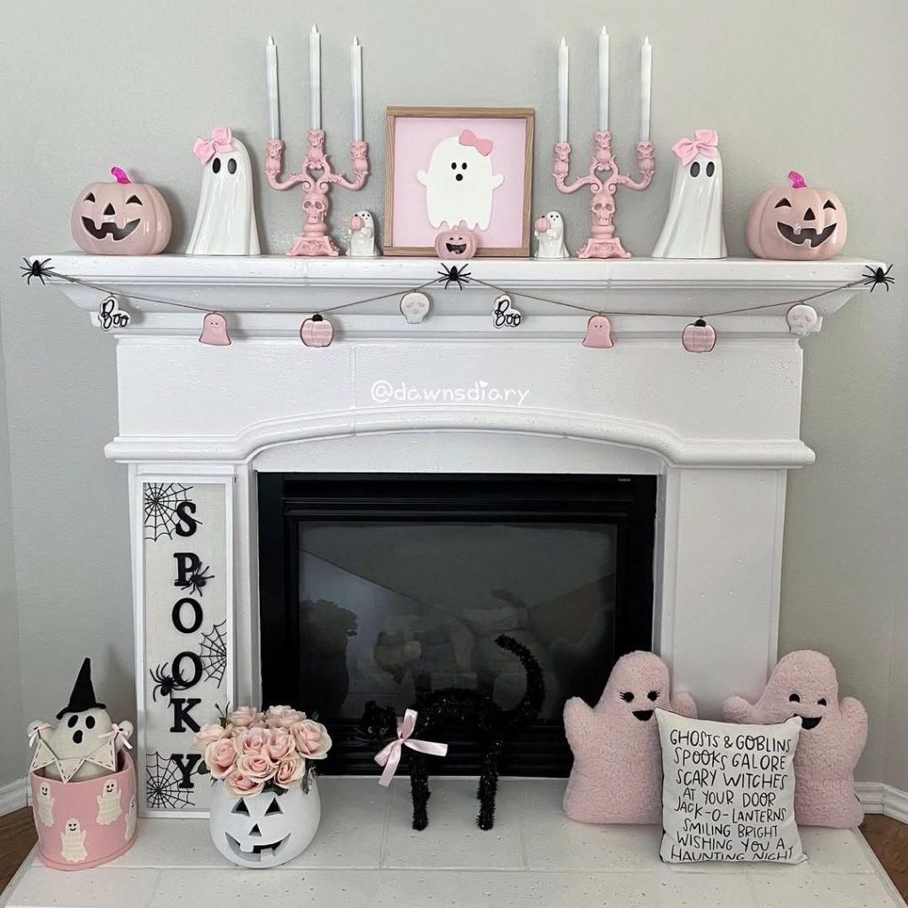 White mantel decorated with pink Halloween theme including ghosts pumpkins and candles