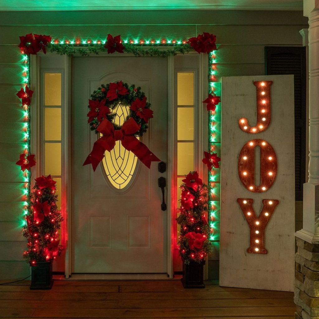 Christmas decorated front porch with wreath lights poinsettias joy sign