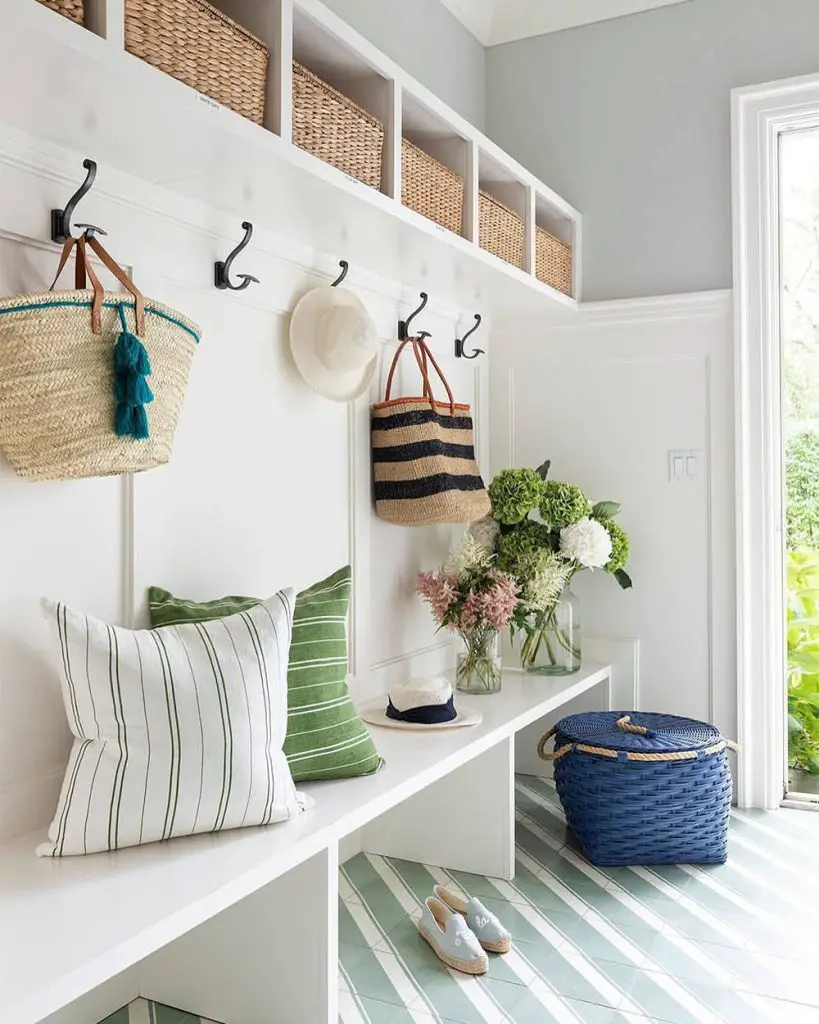Green striped mudroom with white built-ins, wicker baskets, and floral accents