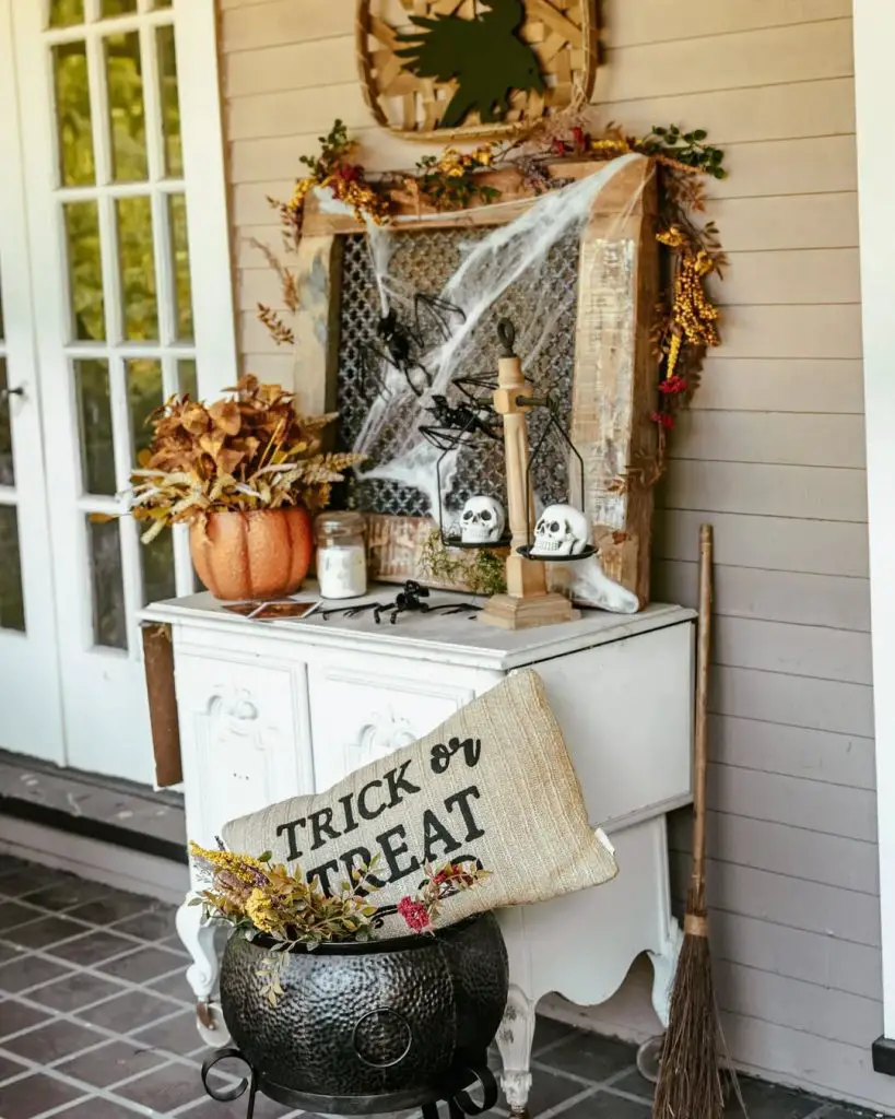 White farmhouse cabinet with Halloween decorations spider webs autumn styling