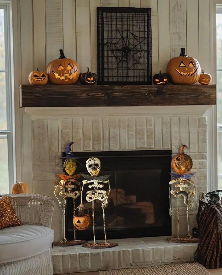 Rustic fireplace mantel with skeleton decorations and carved pumpkins creating farmhouse Halloween display
