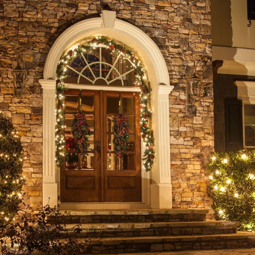 Stone archway entrance with Christmas garland wreaths columns lighting