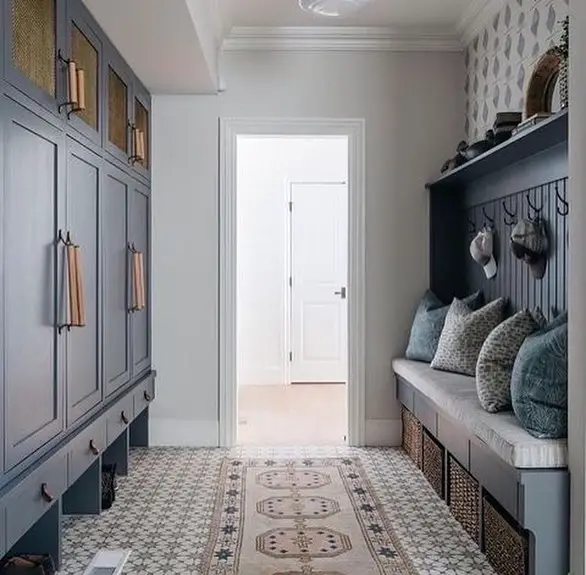 Navy blue mudroom with custom cabinetry, bench seating, and patterned rug