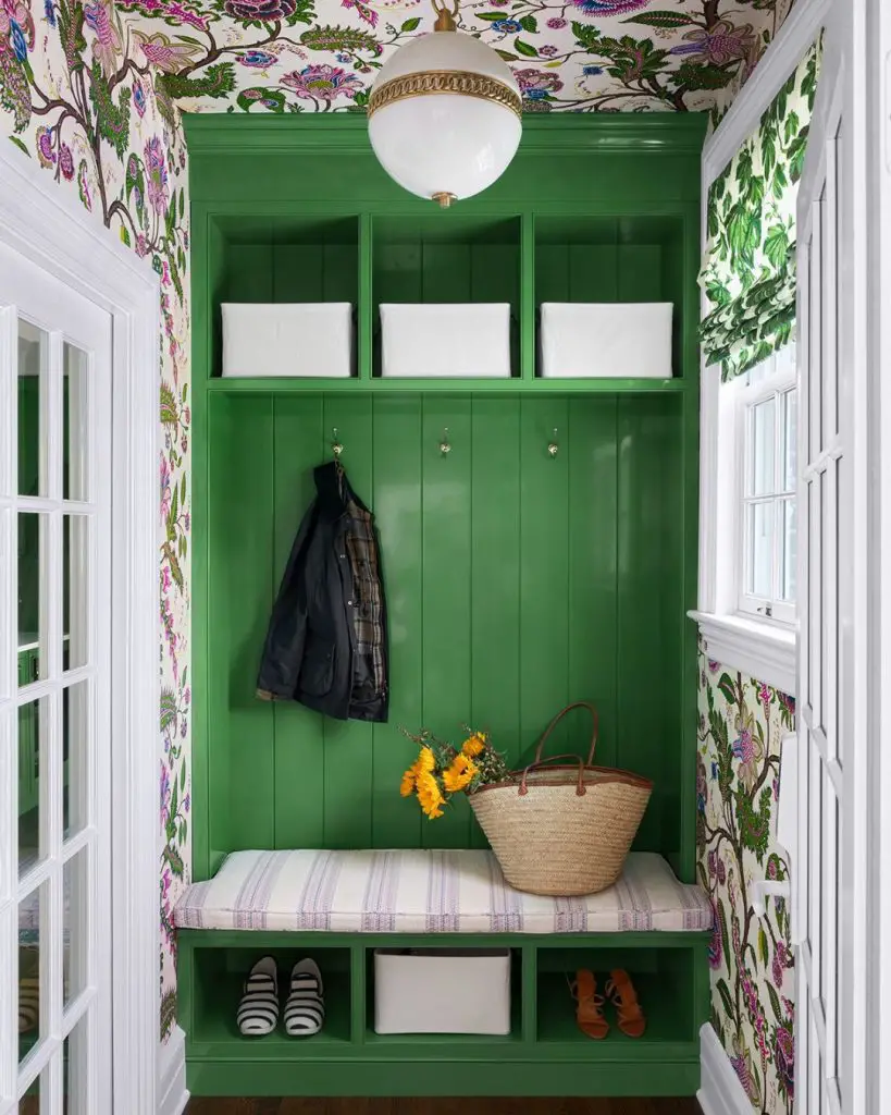 Floral wallpaper mudroom with green cabinets and storage bins