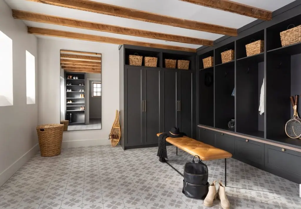 Large mudroom with exposed beams, dark cabinetry, and leather bench