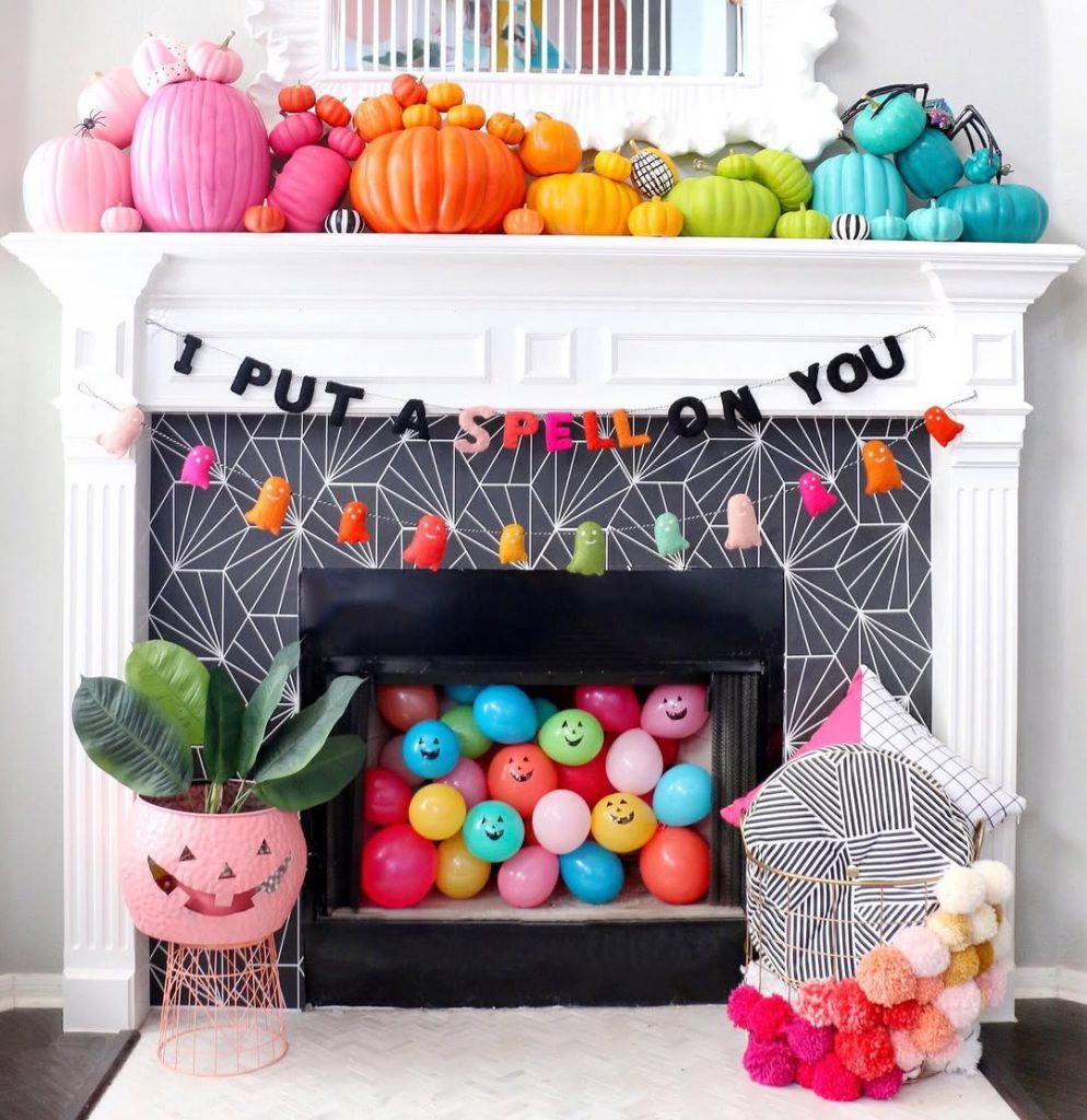Colorful rainbow pumpkin mantel display with bright Halloween decorations and balloons