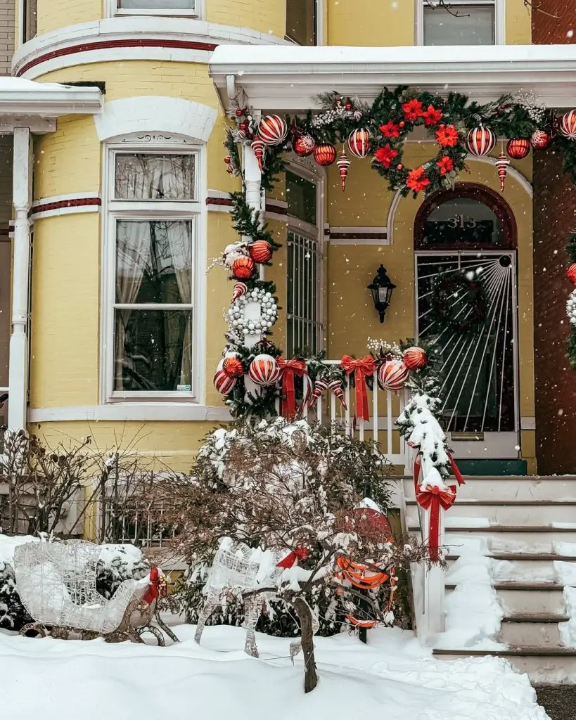 Yellow Victorian house with elaborate Christmas porch decorations and garland