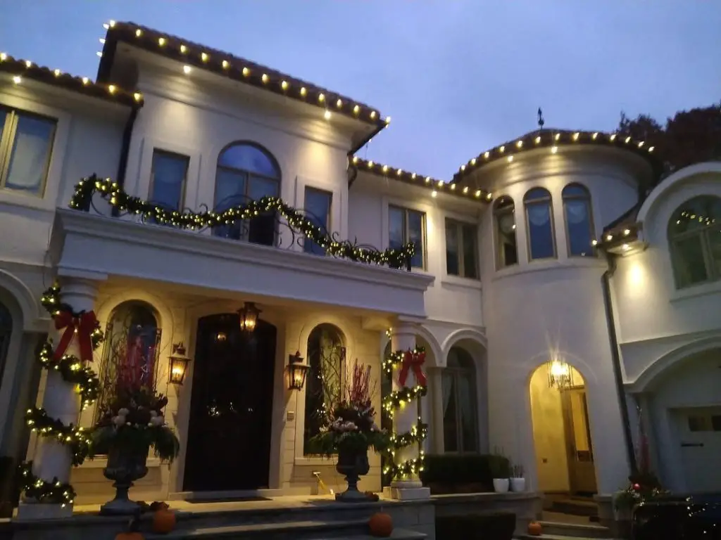Luxury home exterior decorated with professional Christmas lighting and garland