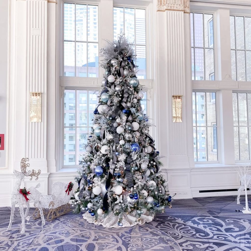 Tall silver Christmas tree in elegant foyer with columns