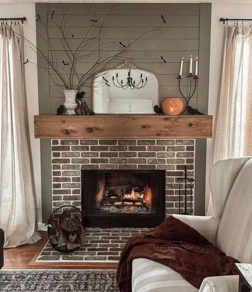 Rustic fireplace mantel decorated with autumn branches candles and pumpkin