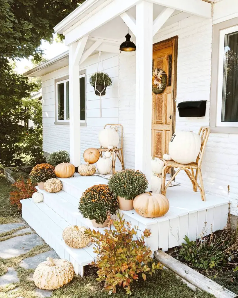 White porch with neutral pumpkins and rattan furniture