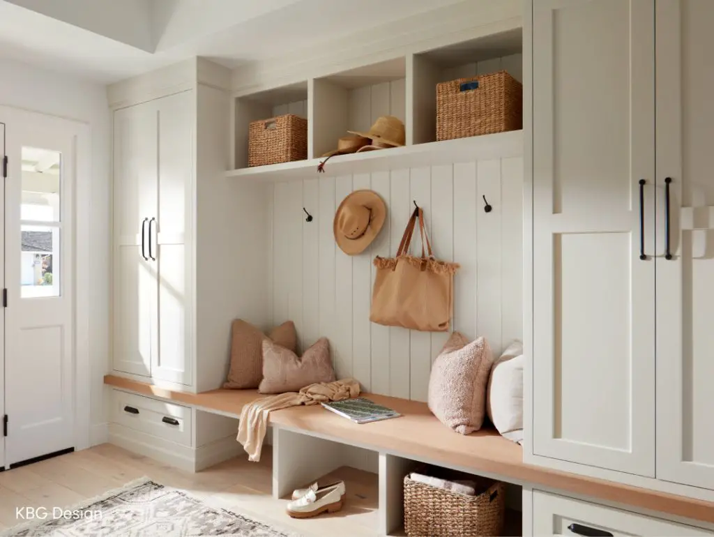 Neutral farmhouse mudroom with wood bench, wicker baskets, and built-in storage