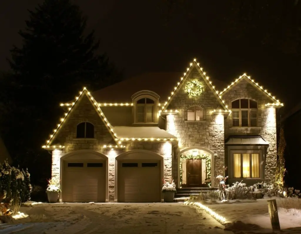 Large stone house with extensive Christmas roofline lighting and garland