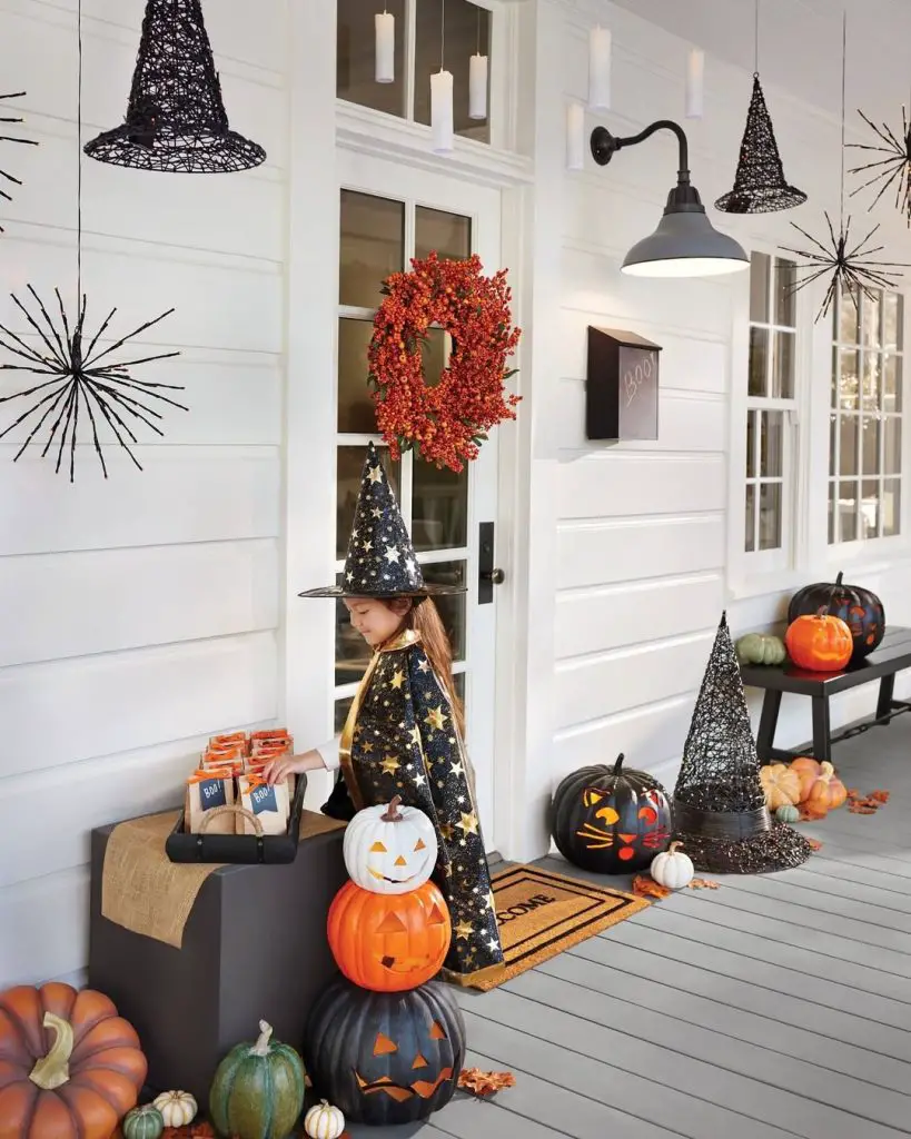 Modern Halloween porch with hanging witch hats child costume pumpkins