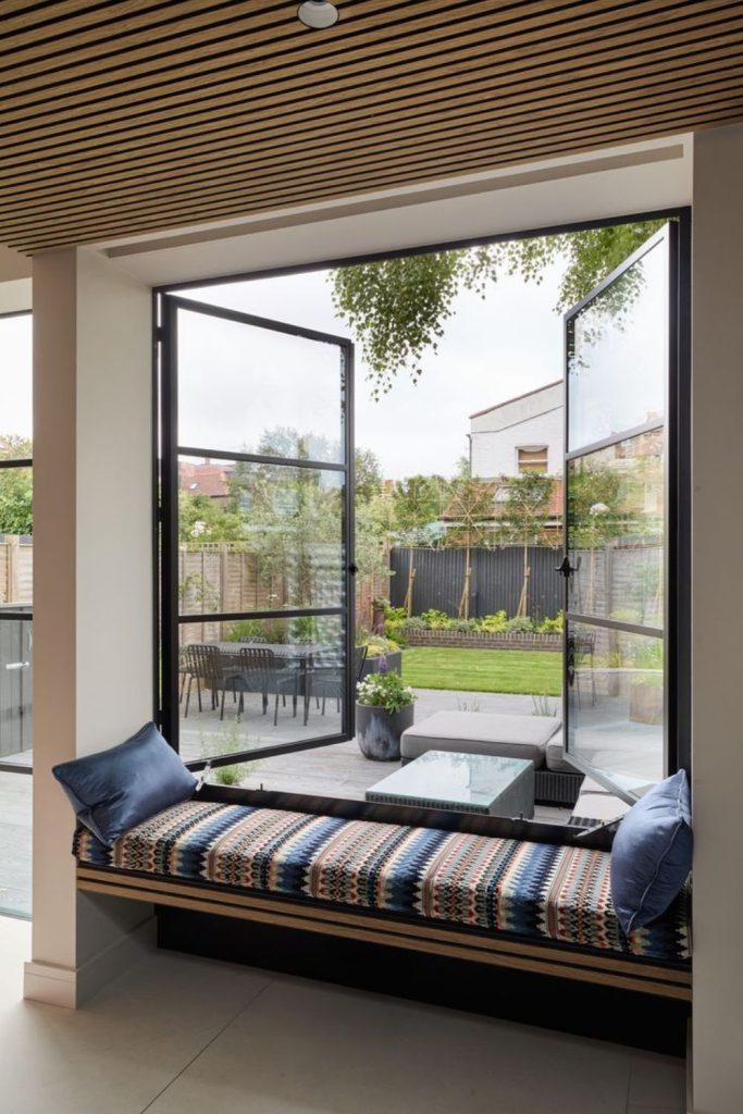 Sleek glass porch with timber bench.