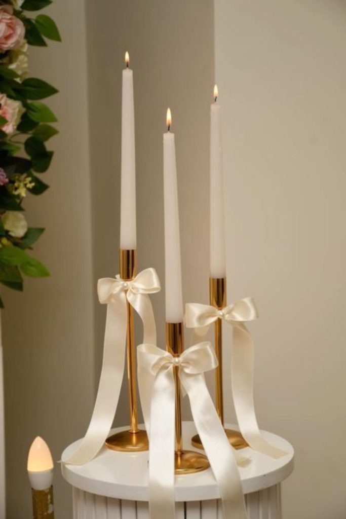 Gold ribbon wrapped candle glass cylinders.