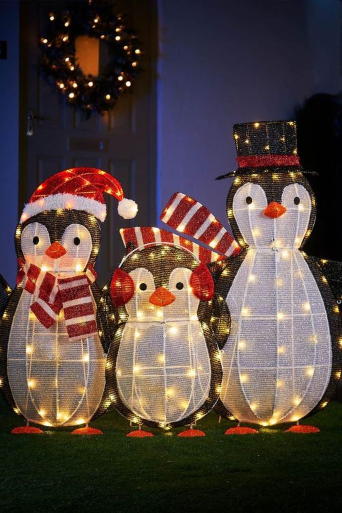 Life-size penguin figurines on snowy lawn