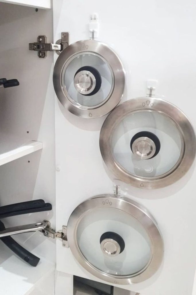 Lids hang on pegboard organized vertically.