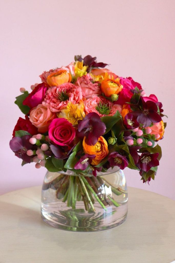 Orange pink proteas in glass bowl
