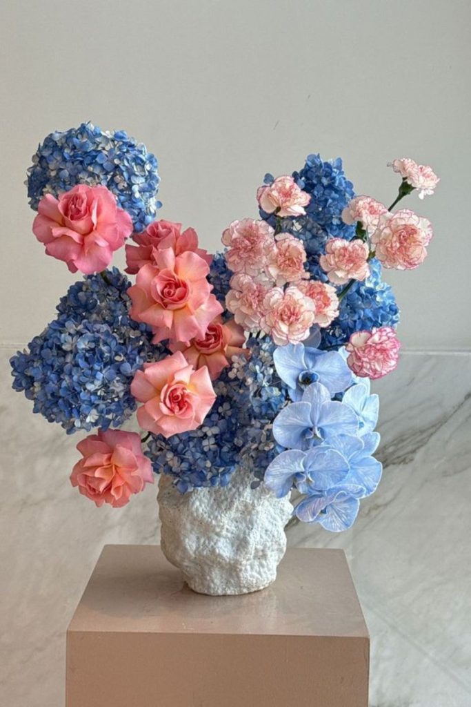Electric-blue delphiniums surrounding coral protea