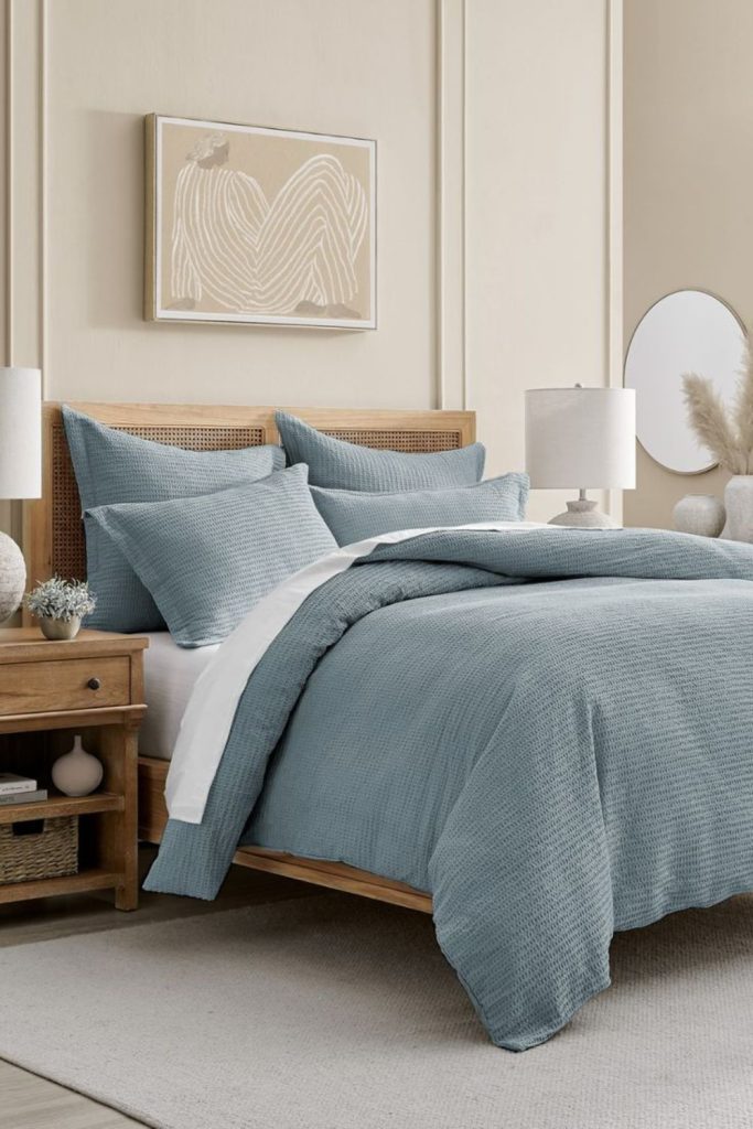 Dusty blue layered bedding with quilts.
