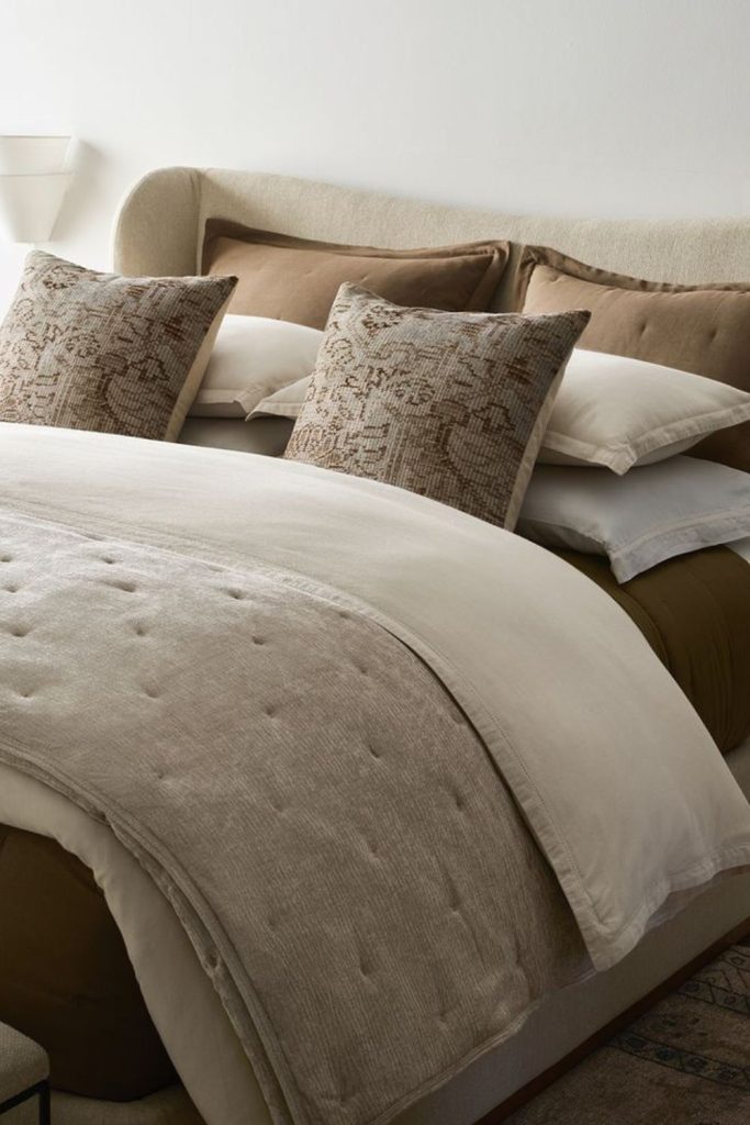 Taupe bedding with layered quilt textures.