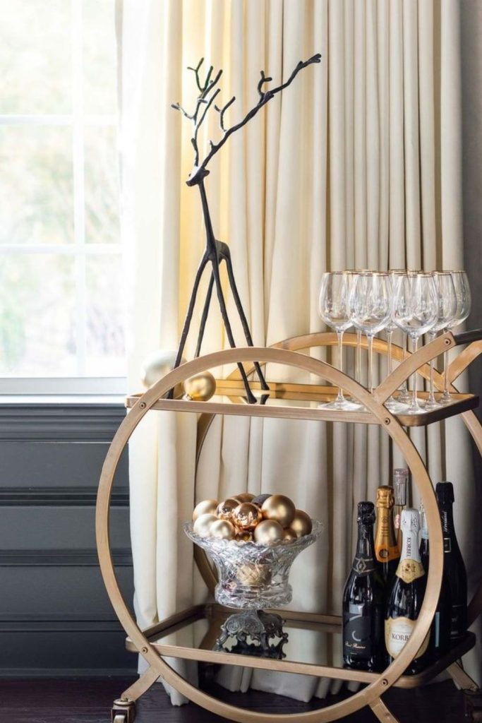 Black and gold Christmas bar cart with ornaments.