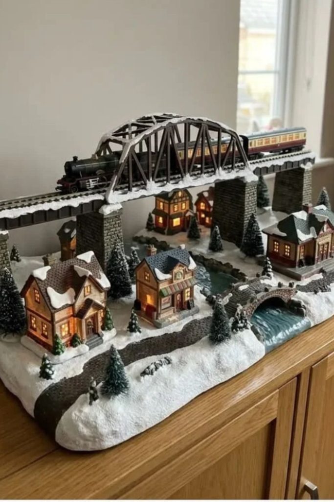 Snowy Christmas village with miniature bridge.